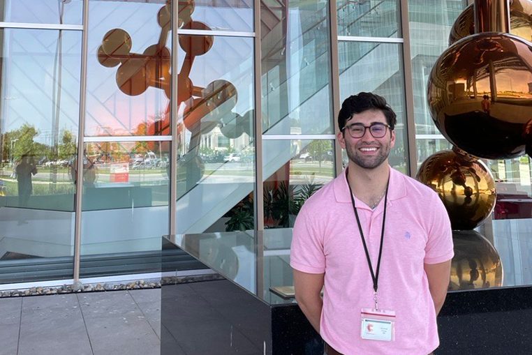 A student intern poses for a photo outside of a modern office bulding