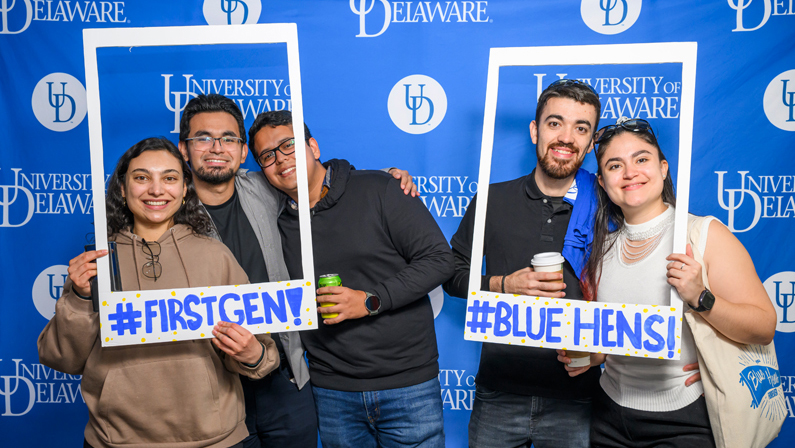 students pose with giant polaroid frames reading #FIRSTGEN and #BLUEHENS