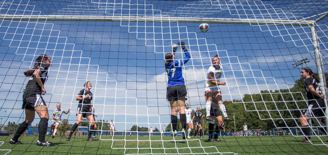 photo of womens soccer game from behind the goal