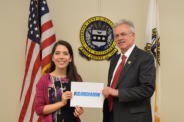 Student and government employer hold sign that reads #UDJobShadow
