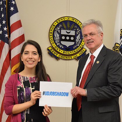 Student and government employer hold sign that reads #UDJobShadow