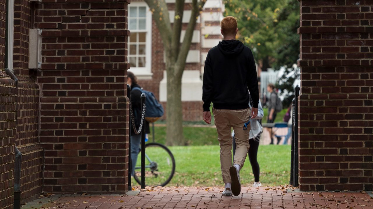 student walking under arches on the Green