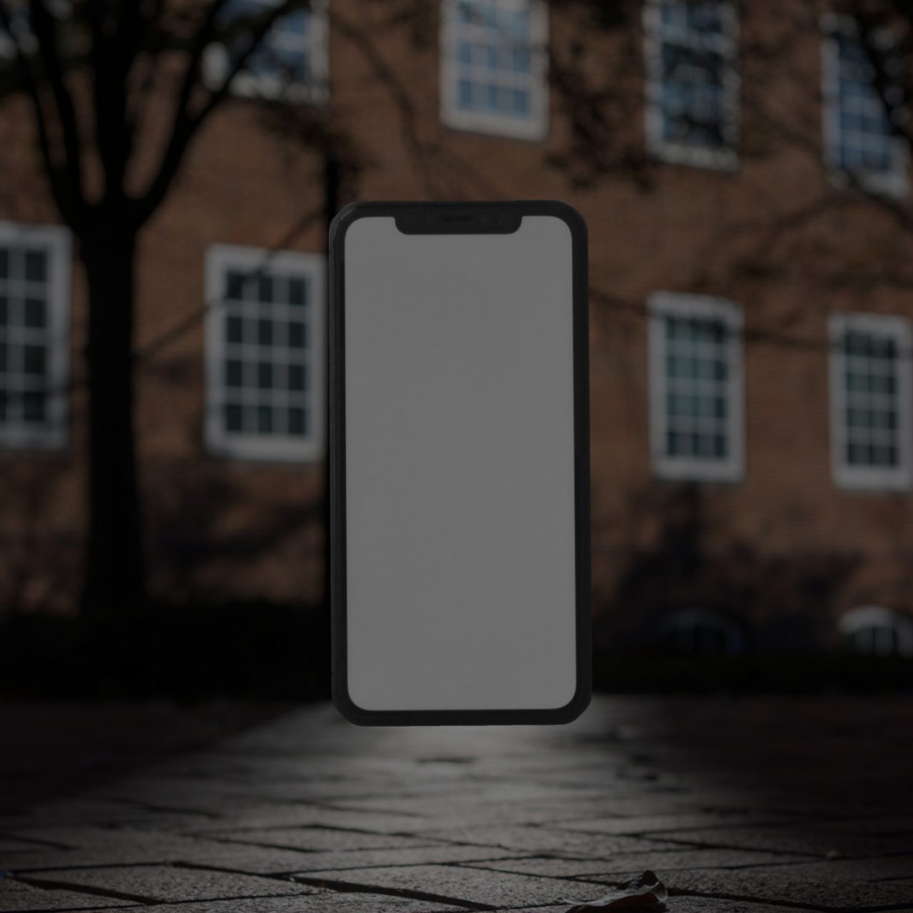 mobile phone against a backdrop of a UD residence hall