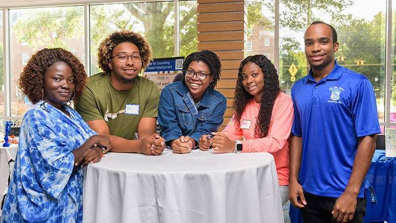 Group of students standing around a table at the First-Generation Day Lunch