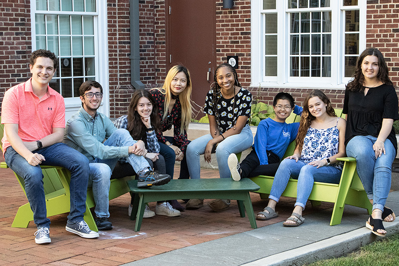 Eight students sit together outside the South Academy residence hall