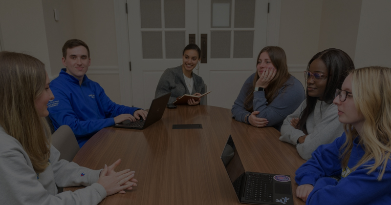 a group of students sits around a table talking