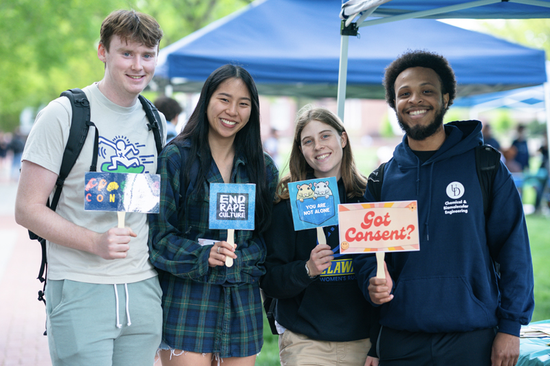 four students hold sexual misconduct support signs at the 2023 Spring Support Fair