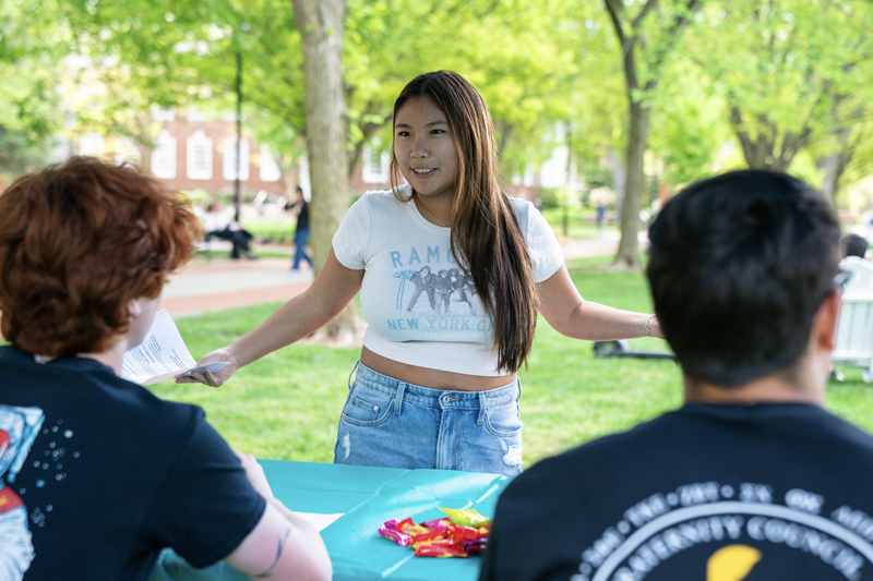 a student talks to two other students at a table at the Support Fair