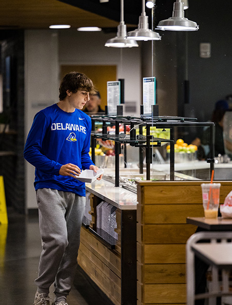A student selects from food options in Caesar Rodney Dining Hall