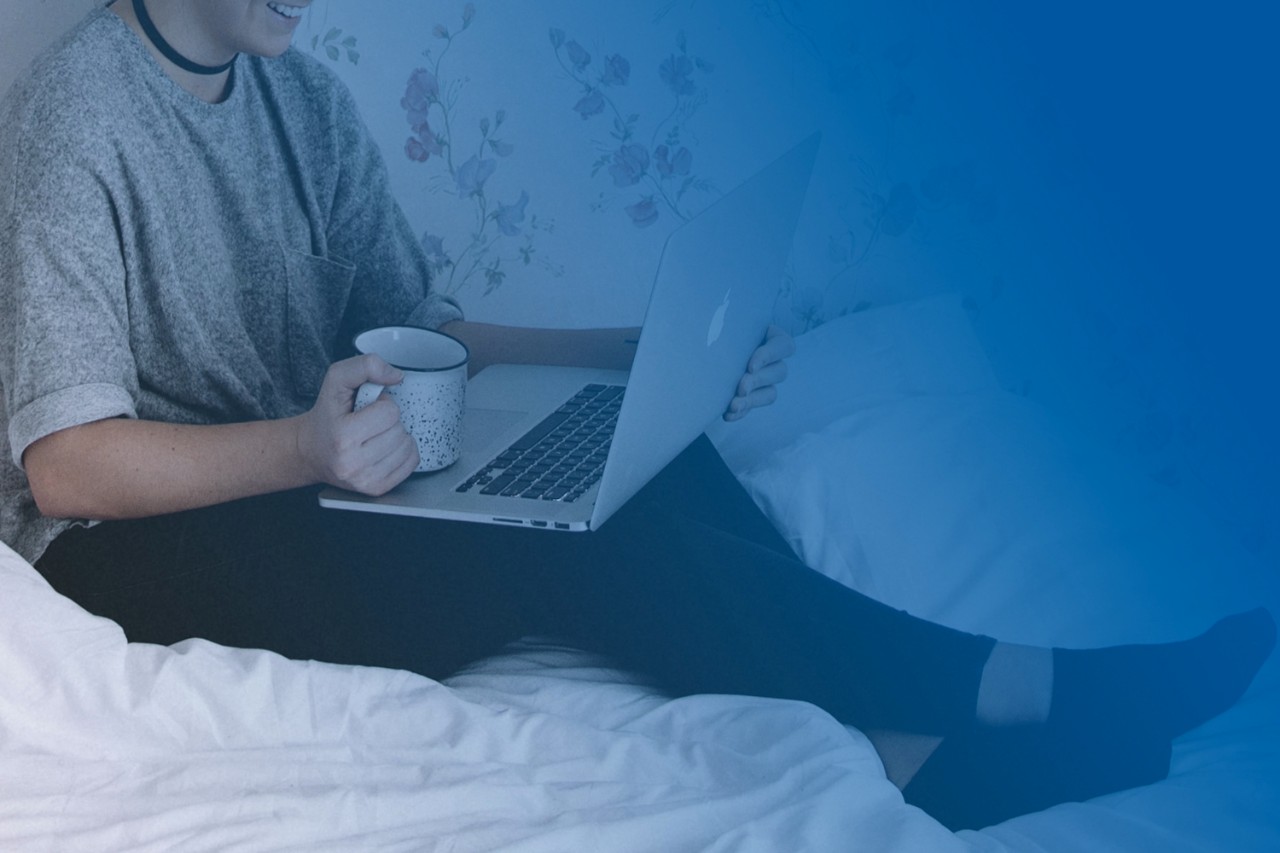 Student using laptop, holding coffee mug