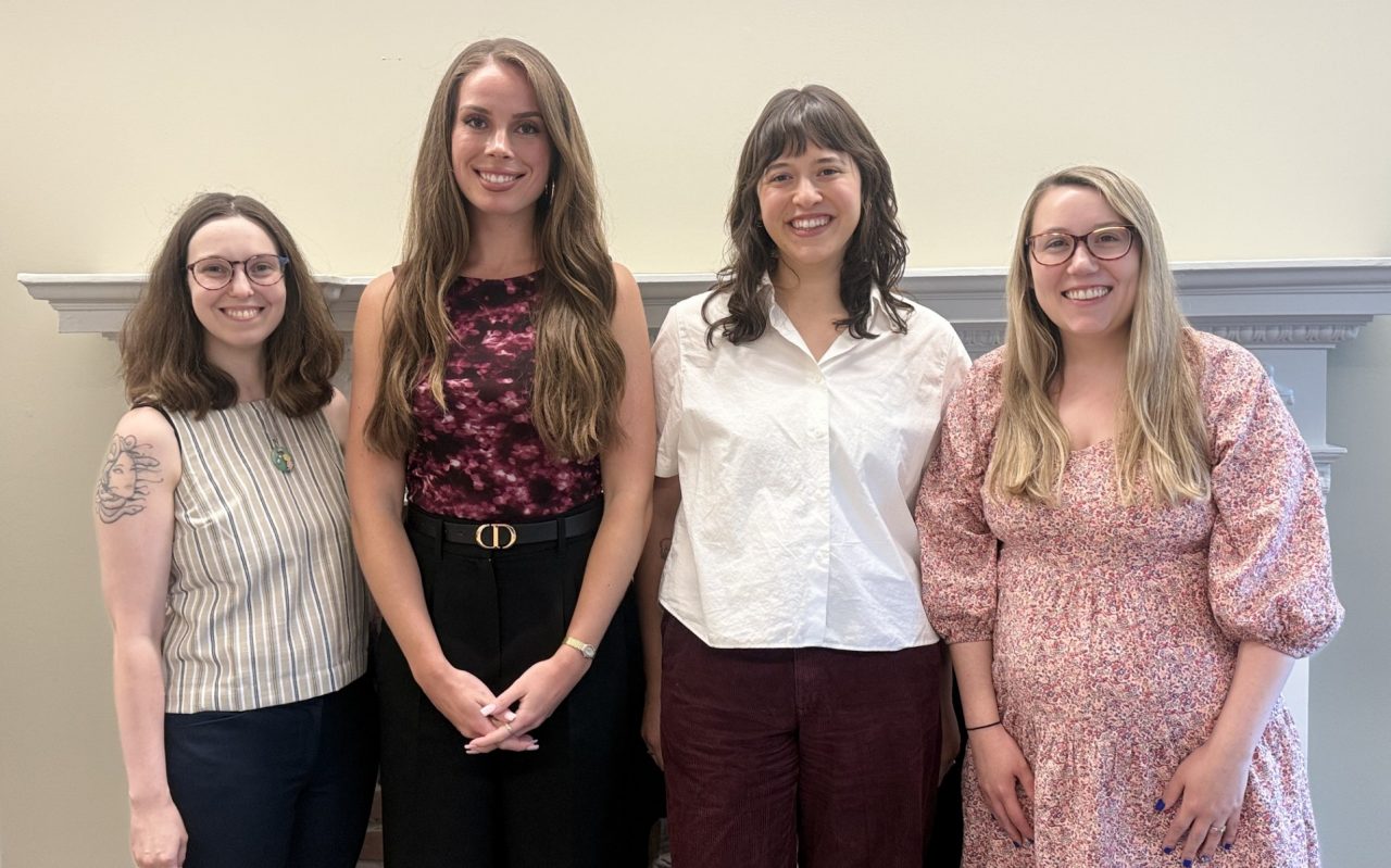 Internship cohort poses together in front of a white wall