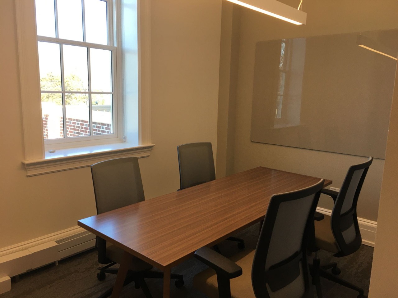 Meeting room with table. four chairs and glass writing board
