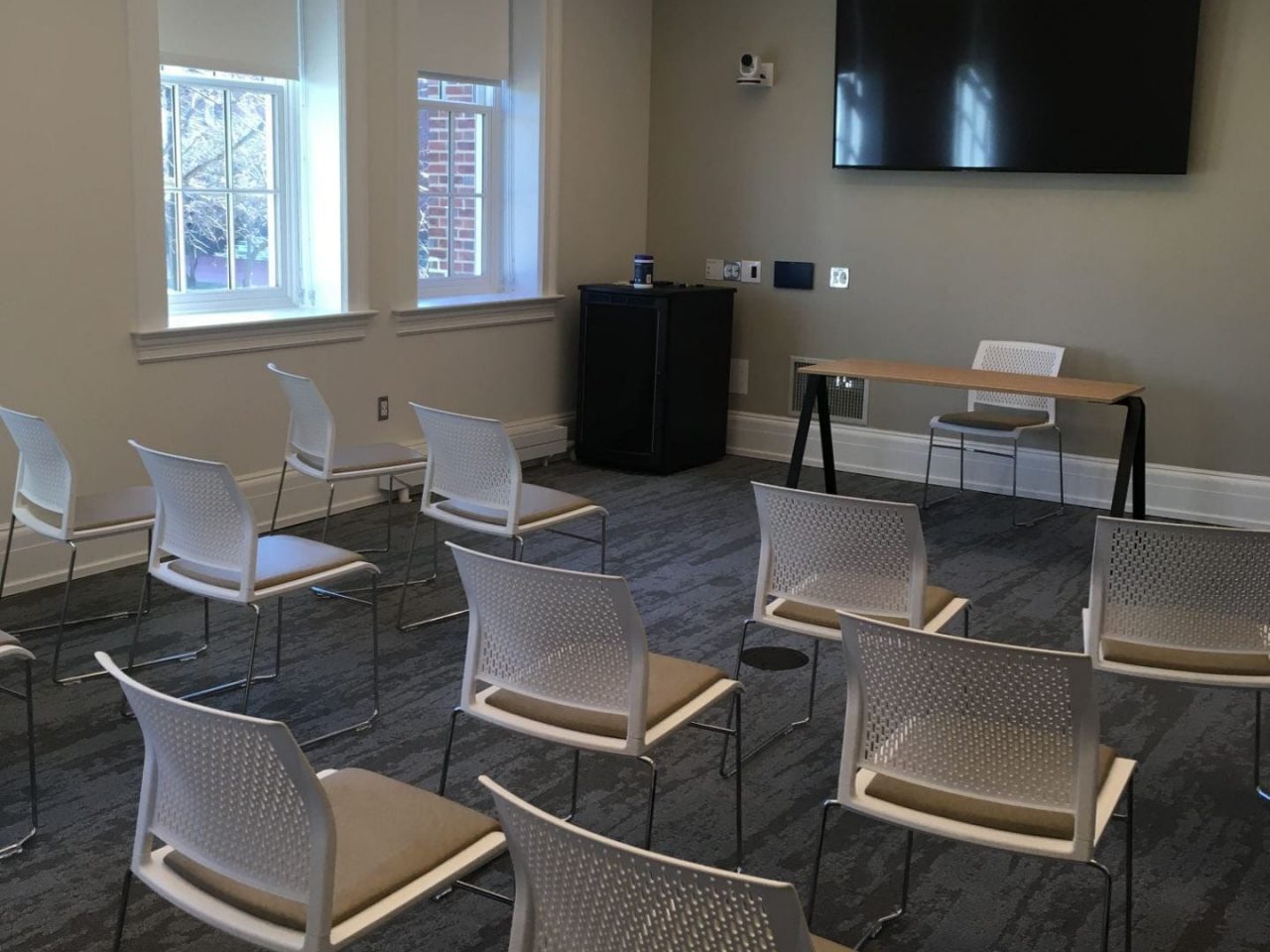 Room with chair arranged in classroom-style and a large digital display