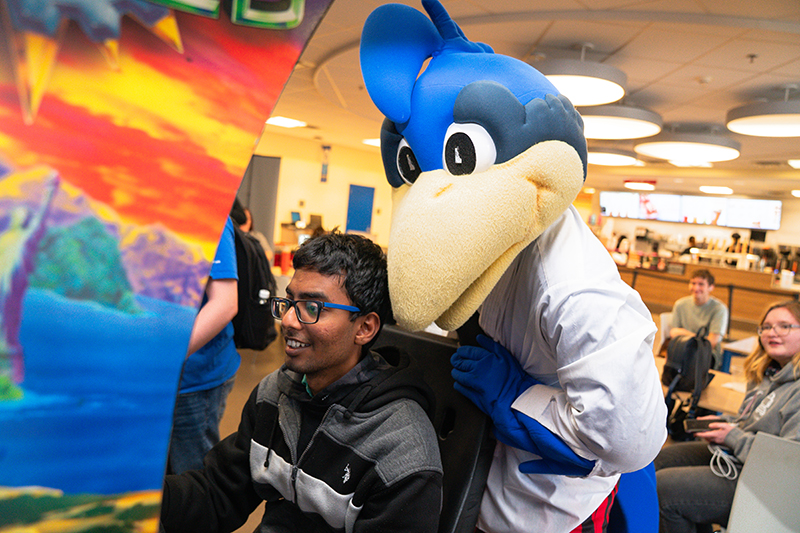 YoUDee watches as a student plays an arcade game