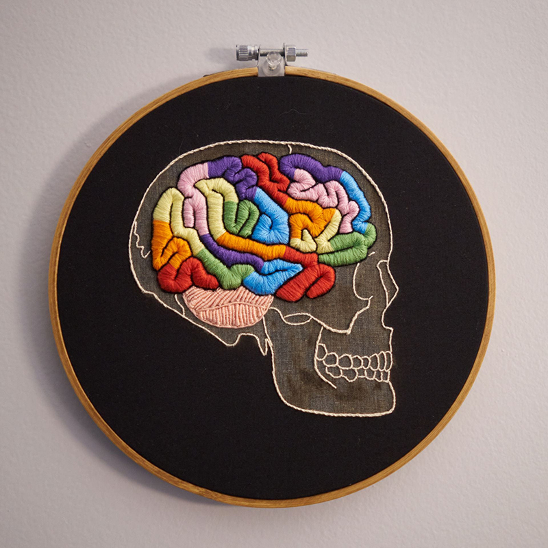 Embroidered skull with multicolored raised satin stitch and bullion knots used to form the shape of a brain