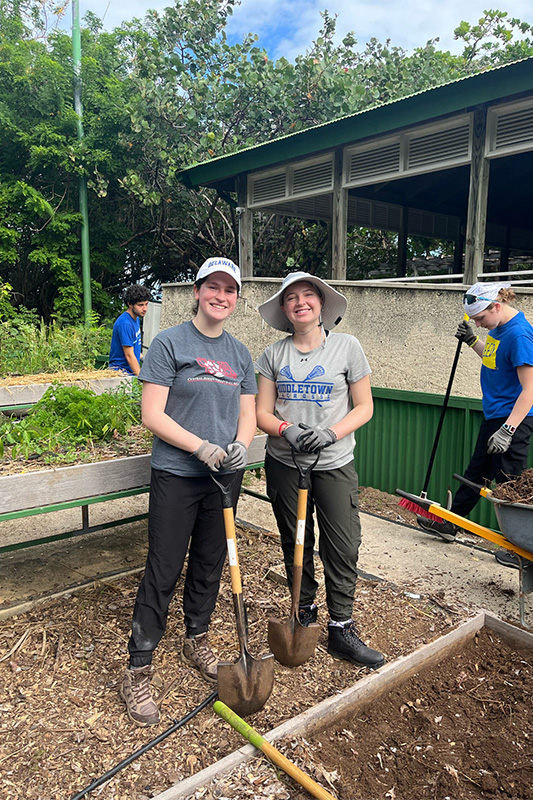 Two students pose with gardening tools