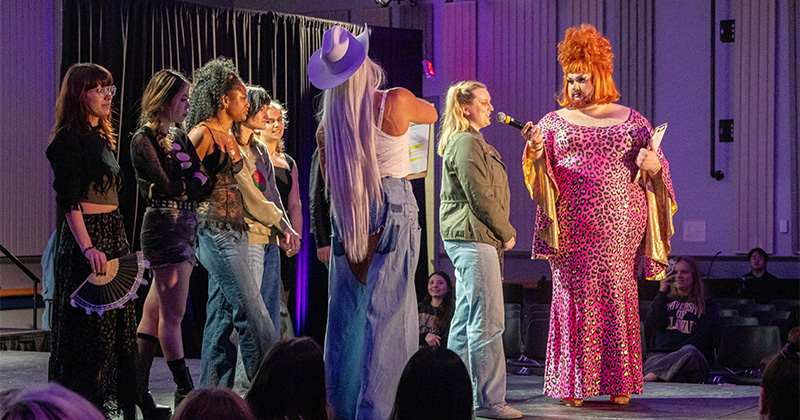 Students on stage with a drag artist