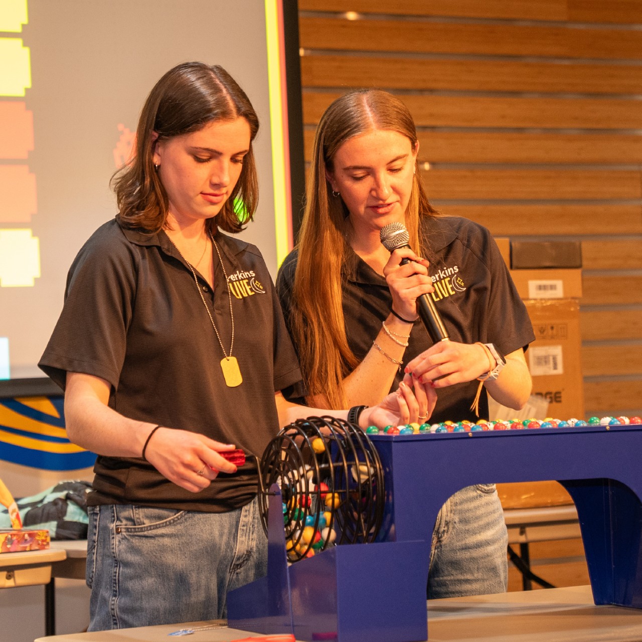 two students draw bingo balls and call out the numbers.