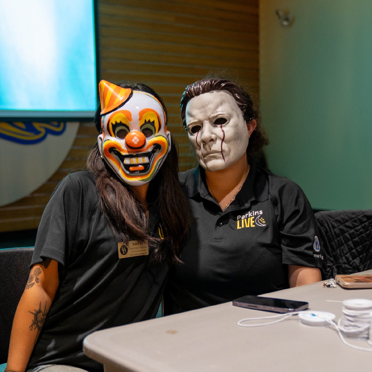 two students wearing Halloween masks pose for the camera