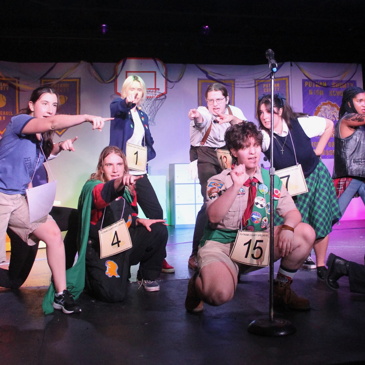 a group of students wearing numbers performs on stage.