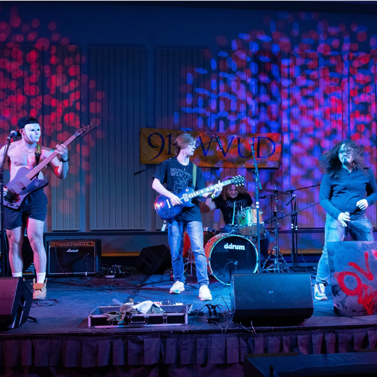 two guitarists, a drummer and a singer perform on stage.