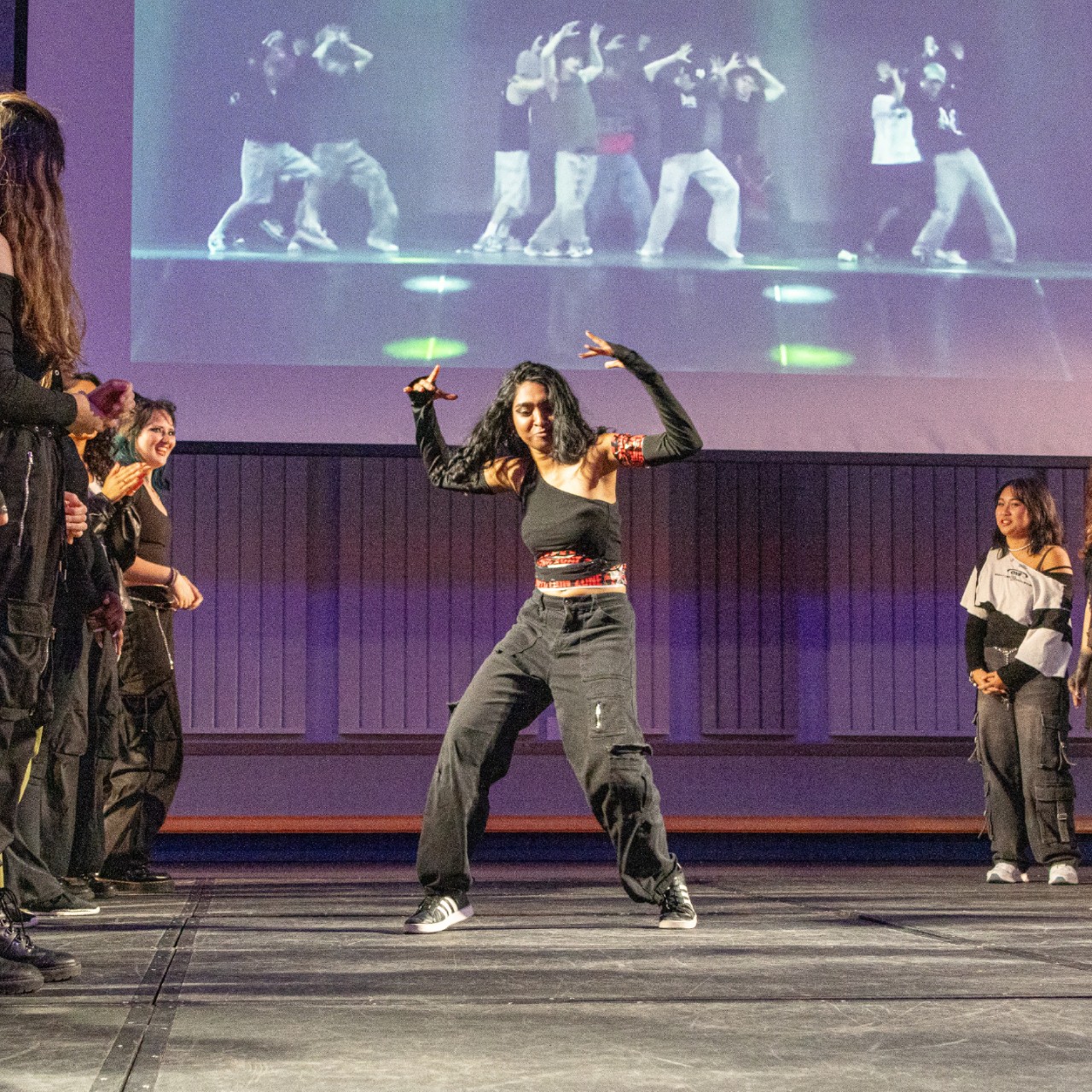 a student dances on stage while others look on