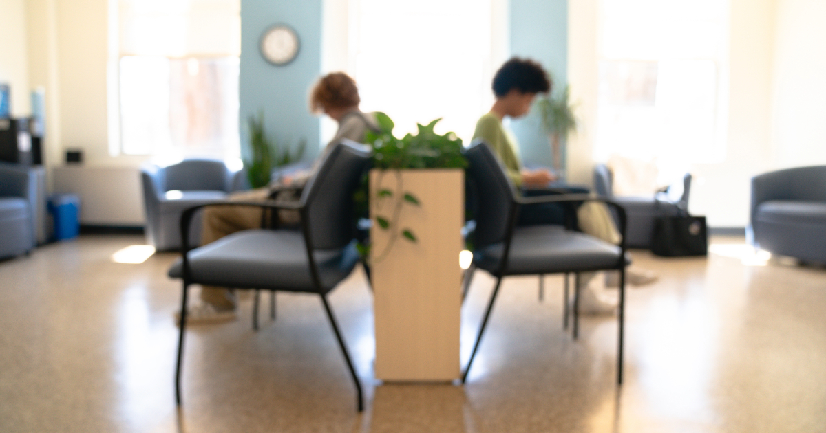 Students sit back to back in blurred waiting room of Student Health Services