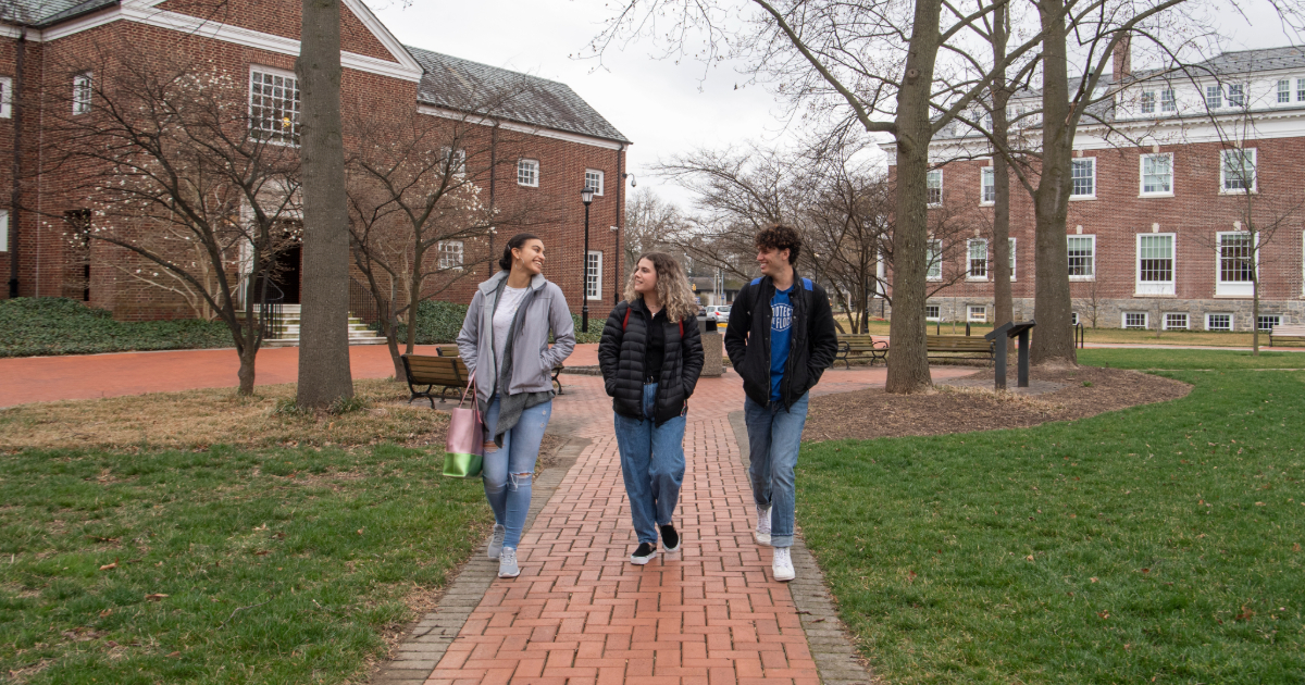 Three students walk outside Warner Hall on The Green