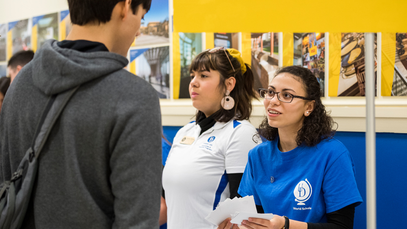 a staff member in a UD World Scholars shirt assists a student at NSO