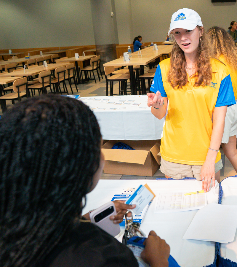 a greeter at NSO talks to a student picking up her name tag