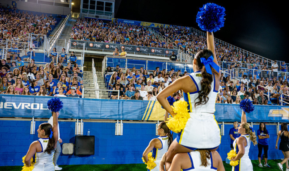 Cheerleading team performs for a crowd of students