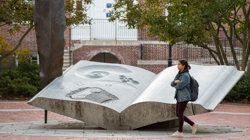 a student walks by the Wings of Thought statue at UD's Mentor's Circle