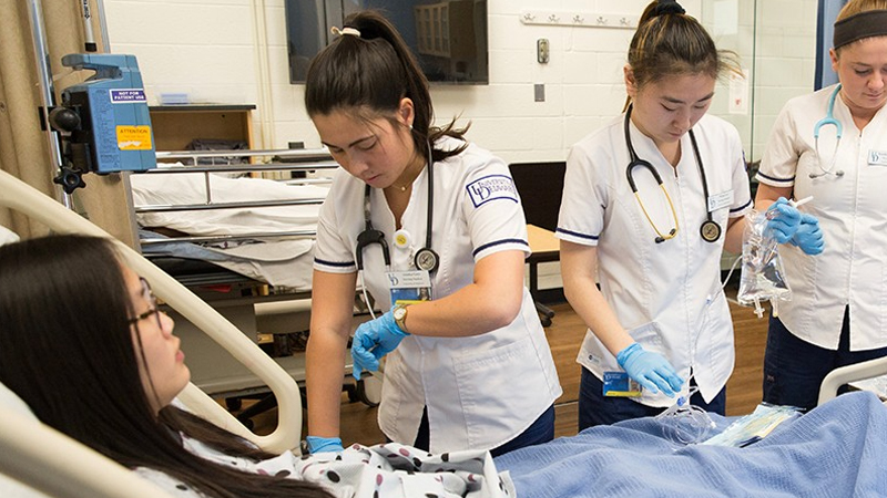 three nursing students practice working on a fellow student.