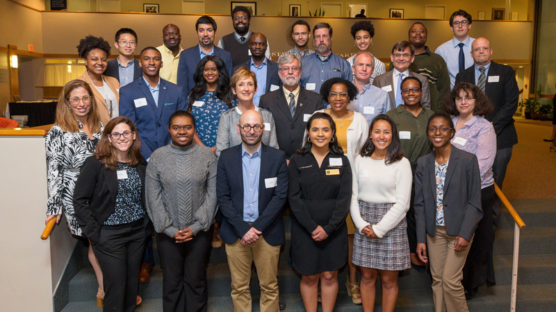 a group of Honors students poses with faculty on steps inside Clayton Hall.