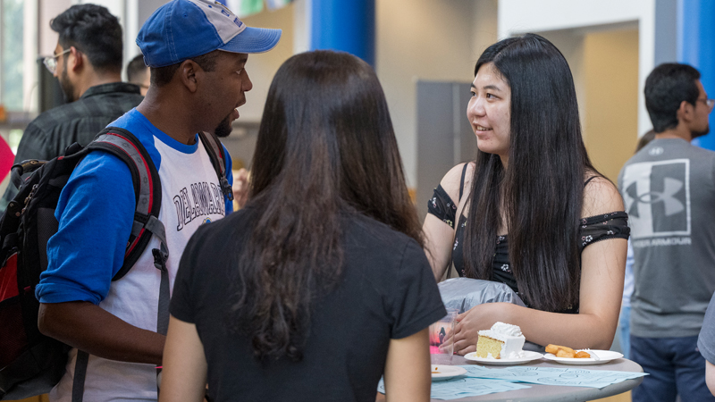three students talk at a table at UD's International Student NSO.