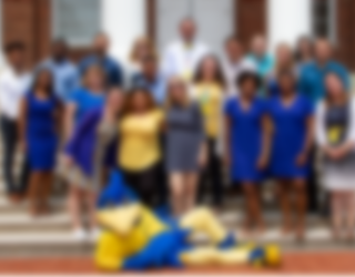 Smiling photo of our staff with the UD mascot, YoUDee.
