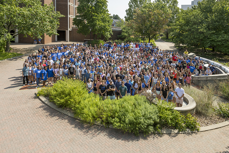 Group of honors students standing outside surrounded by greenery. 