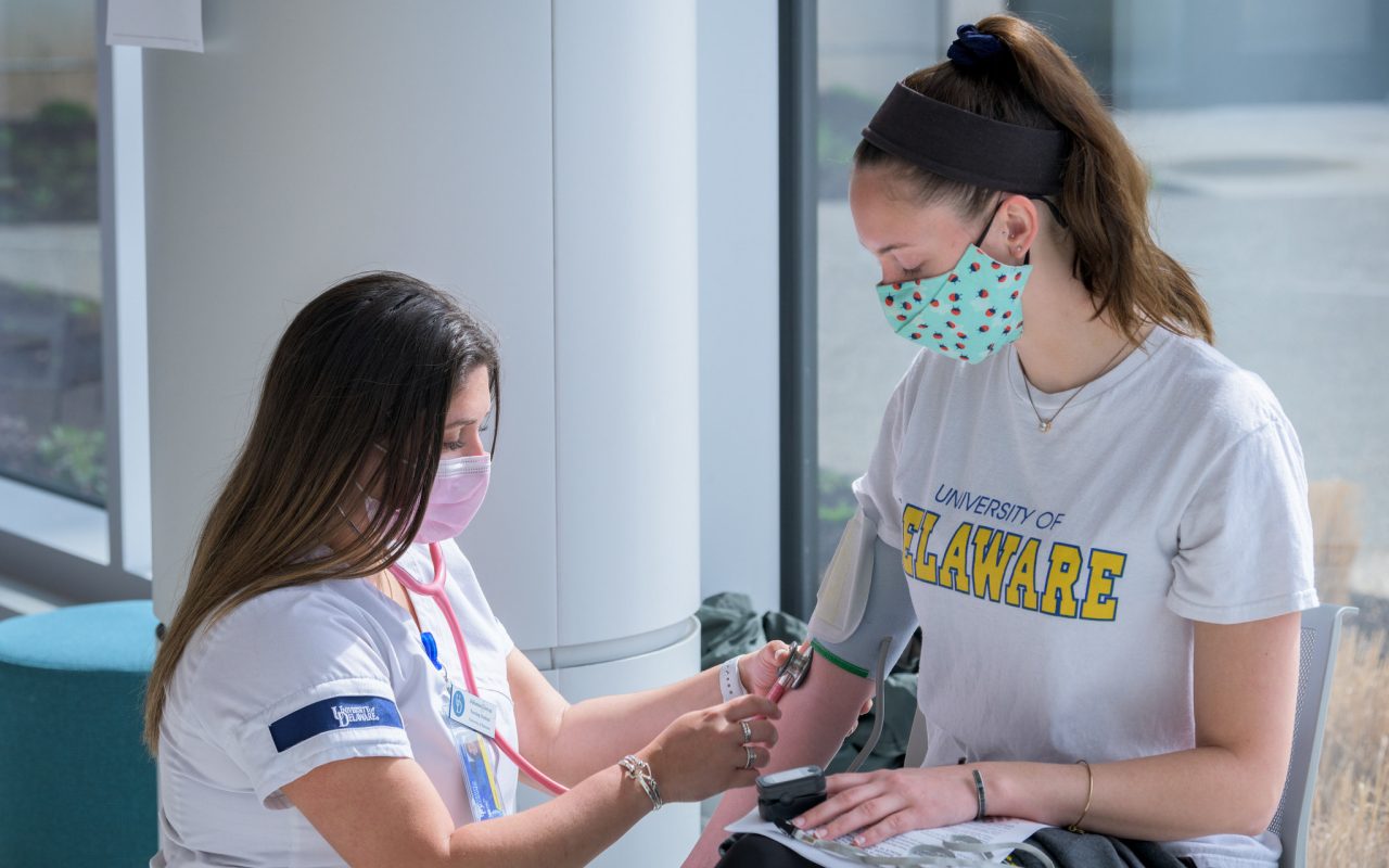 OCM-COVID-19-Higher_Ed_Vaccination_Clinic-040121 COVID-19 vaccination clinic held by Albertsons / Acme markets in the University of Delaware’s STAR Tower. Targeted specifically at specifically for employees and those affiliated with institutions of higher education in the state of Delaware.
Pictured: After receiving her COVID-19 vaccination, Hannah Gentry (right), a Junior Biomedical Engineering major (Class of 2022) has her vitals checked by Julianna Giovan, a Senior Nursing Student (Class of 2021)