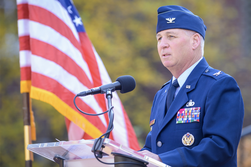 a man in a military uniform gives a speech from a podium with an American flag in the background