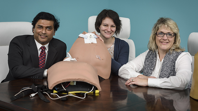 Cowperthwait QED Award Amy Cowperthwait, College of Health Sciences along with her partners Amy Bucha (darker hair) and Joy Goswami from OEIP (Office of Economic, Innovation and Partnerships look over the latest model of their SimuTrach.