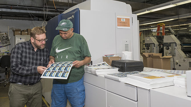 Mike Czerepak, Director and Talel Radhouani, Digital Printing Tech both from University Printing work alongside 3 new machines recently aquired by the department, the larger of the group is unique in that it can print in CMYK with a 5th color of blue to help correctly match the UD blue instilled by the style guide.