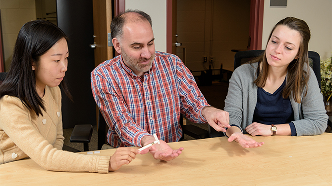 Assistant professor of Psychological and Brain Sciences Jared Medina, works with 2 of his grad students - Yuqi Liu and Kaylee Vietz - to demonstrate the effect of "mirror-touch synesthesia." The condition causes a person to experience "touch on their own body when observing someone else being touched." [psych.udel.edu] - (Evan Krape / University of Delaware)