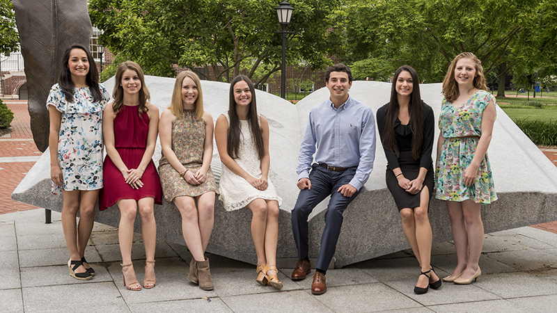 The 4.0 Seniors for 2017 - Abigail Osborn (white lace dress), Sarah Rice (multicolored floral dress), Tori Sanders (red dress), Christina Gulla (white dress with blue flowers/dark hair), Catherine Dolan (multicolored floral dress, blonde hair), Victoria Longo (black dress) and Michael Lino ( only guy).