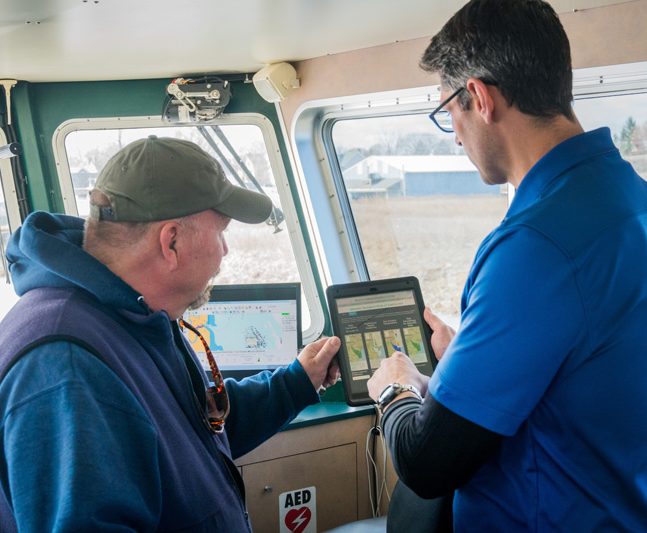 Matt Oliver and Captain Mike Garvilla on the R/V First State in Leipsic looking at the Atlantic Sturgeon forecast app.