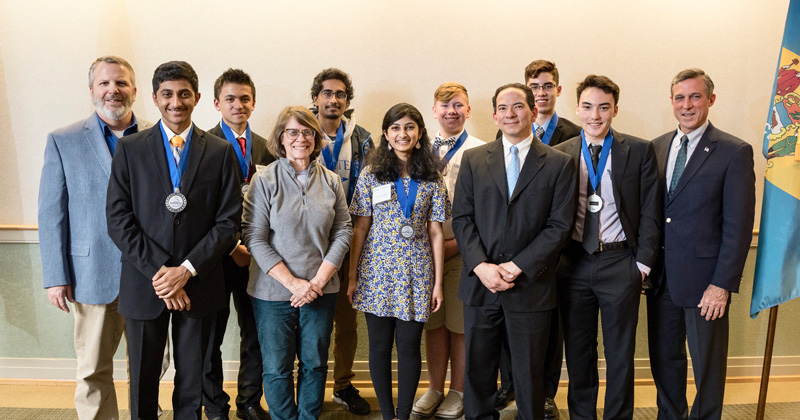 Delaware Gov. John Carney (far right) and the Delaware Biotechnology Institute recognized the Delaware BioGENEius Challenge finalists and some of the teachers who helped them along the way. Front row, from left: Ashish D’Souza, Rose Lounsbury, Preeti Krishnamani, Dr. John Koh, Benjamin Dubner. Back row, from left: Robert Bogdziewicz, Max Medroso, Karna Nagalla, Jacob Smith, Connor Barrett, Gov. Carney. 