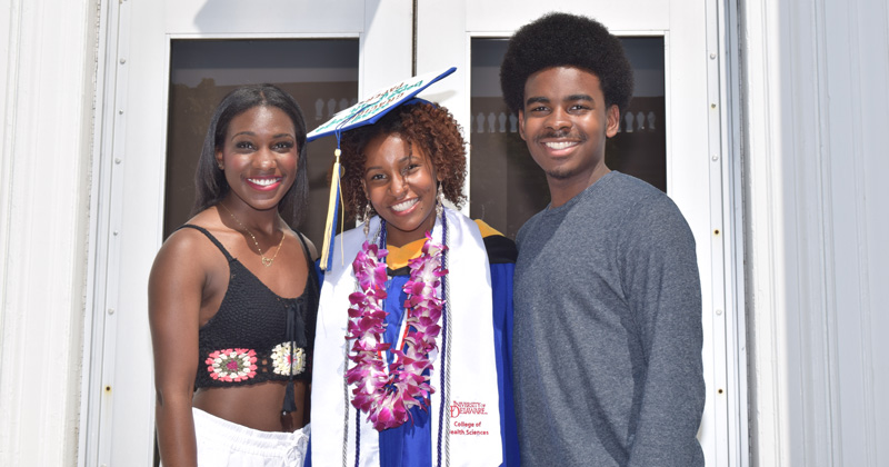 From left to right: Chisholm siblings Sharlie, Briyana and Taurence Chisholm Jr. celebrate at Briyana’s UD graduation in spring 2018.