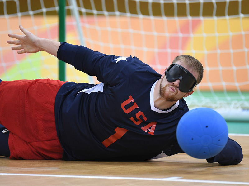 Andy Jenks blocks an opponent’s throw during goalball competition at the 2016 Paralympic Games in Rio de Janeiro, where the U.S. men’s team won a silver medal. Goalball players wear dark eye shades to equalize conditions among athletes with different degrees of visual impairment. The ball contains bells that players use to track its movement. 