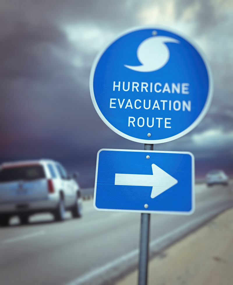 Detail of hurricane evacuation route sign on highway and escaping cars