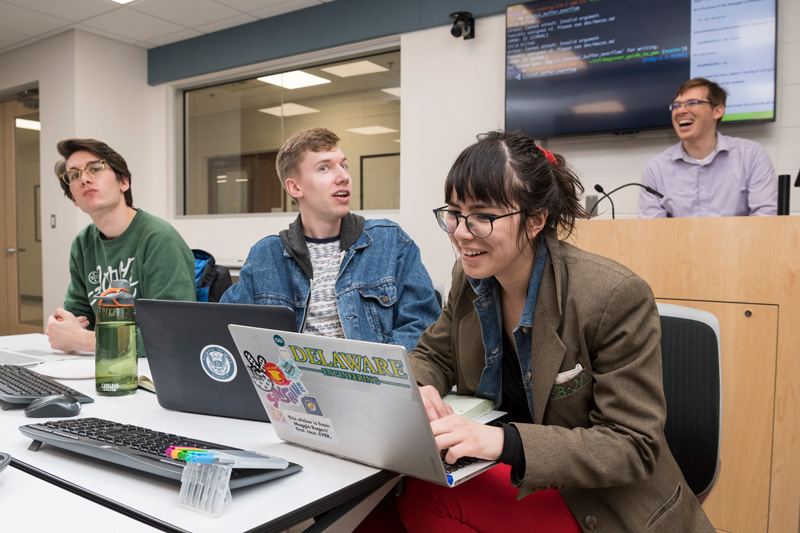 Dr. Andy Novocin teaches students developing and practicing cybersecurity skills to make them more “ethical” hackers in the world of cybersecurity in the iSuite at Evans Hall, Friday, March 22nd, 2019.  Students are: Dan Goodman (gray long sleeve), Vineeth Gutta (black shirt, khakis), Landon JOnes (black jacket), Ryan Geary (green crewneck), Thomas Pisklak (striped t-shirt), Isabel Navarro (red pants, brown blazer), Collin Clark (jean jacket, nose piercing), And Alena Gusakov (red shirt, jeans)  (PHOTO RELEASES WERE OBTAINED ON ALL PICTURED.)