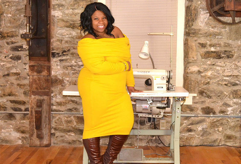 Alum Cha Cha Hudson stands with a sewing machine